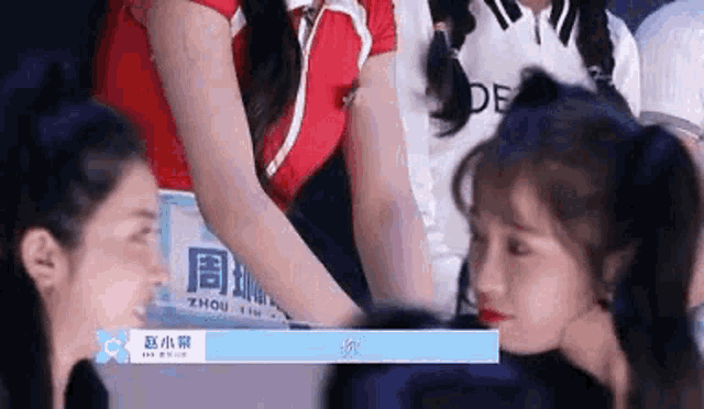 a group of girls are standing next to each other in a room and talking to each other .