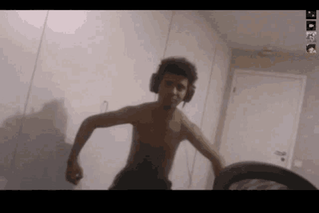 a shirtless man wearing headphones stands in a room