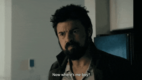 a man with a beard is standing in a kitchen talking to someone .