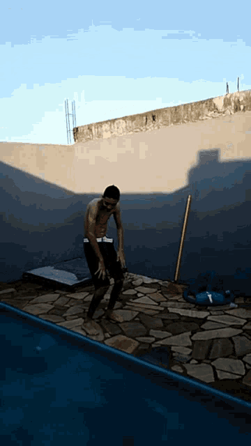 a man standing in front of a pool with a mop on the ground