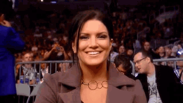 a woman is smiling while sitting in front of a crowd of people .