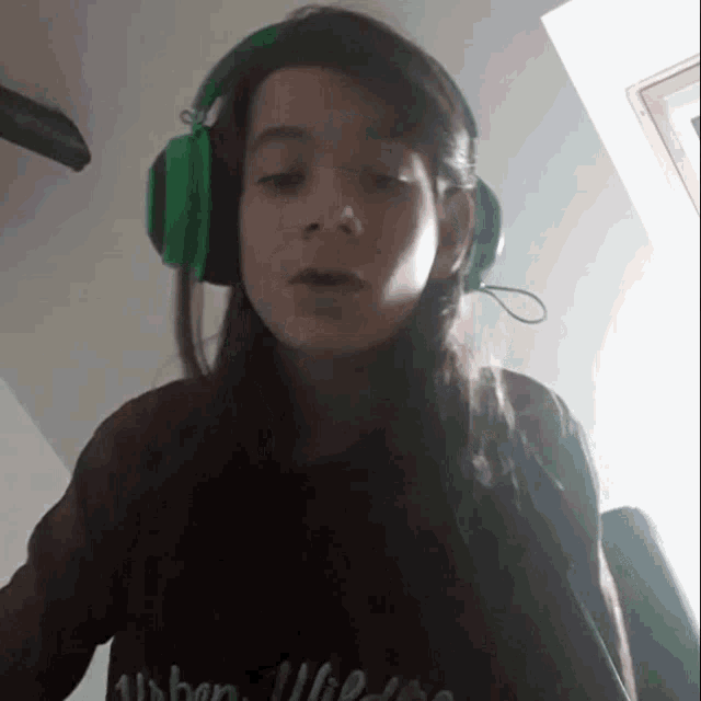 a young girl wearing green headphones and a urban life shirt