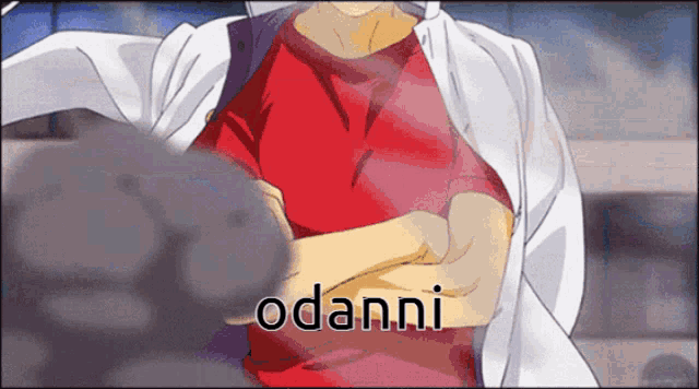 a man in a red shirt stands with his arms crossed and the word odanni is visible