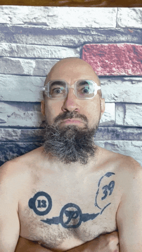 a man with glasses and a beard has a tattoo on his chest that says 39