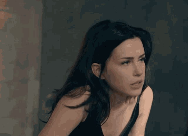a woman in a black tank top is looking to the side