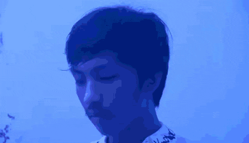 a young man is drinking a glass of water in a blue room .