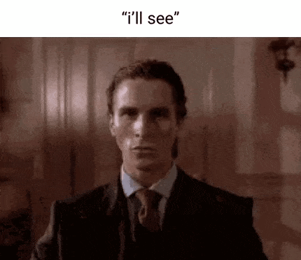 a man in a suit and tie is standing in a room and talking to someone .