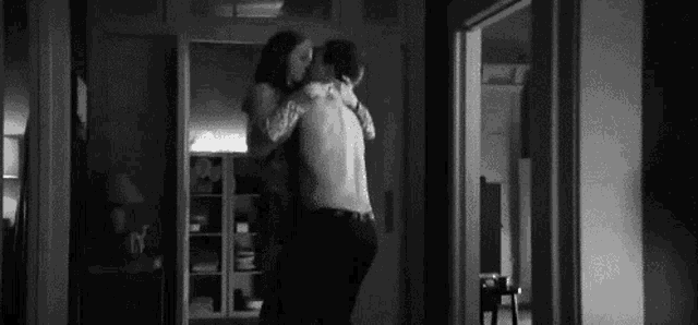 a man and a woman are hugging each other in a hallway .