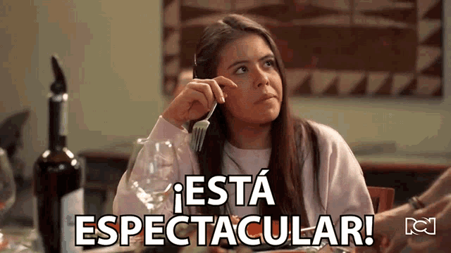 a woman sitting at a table with a fork in her hand and the words esta espectacular written on the bottom