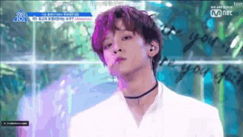 a young man with a choker looks at the camera in front of a sign that says 101
