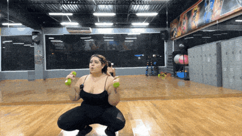 a woman squatting with dumbbells in a gym