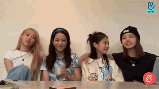 a group of girls are sitting at a table with their arms around each other
