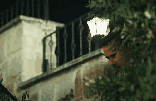 a man is standing in front of a building with a lamp on the balcony .
