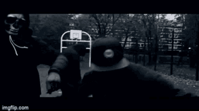 a group of people are standing in front of a basketball hoop in a park .