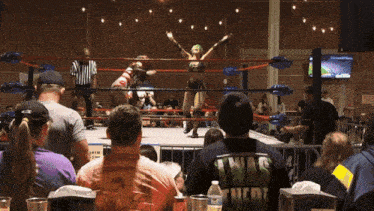 a man wearing a texas shirt watches a wrestler in the ring
