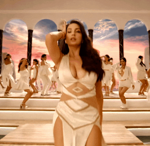 a woman in a white dress is standing in front of a group of women