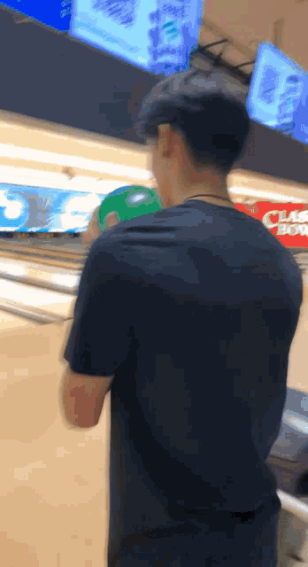 a man holding a bowling ball in a bowling alley