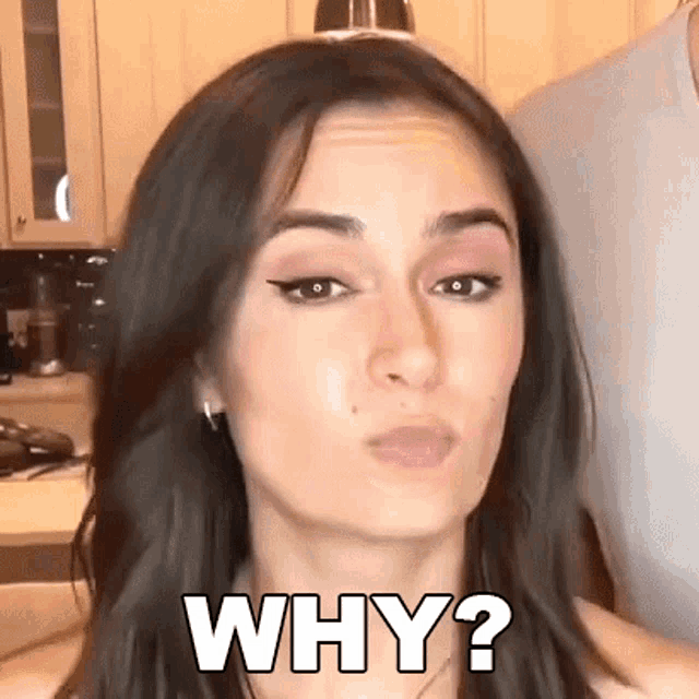 a woman is making a face and saying `` why ? '' in a kitchen .