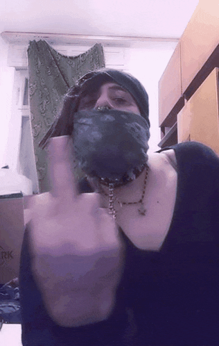 a woman wearing a bandana and a choker giving the middle finger