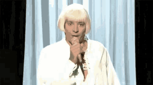 a man with a wig is singing into a microphone .