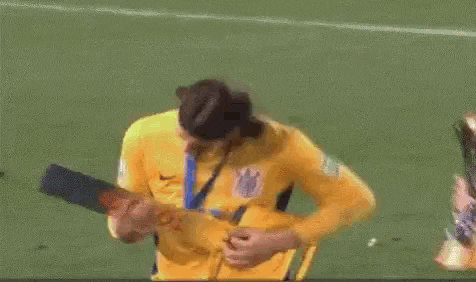 a soccer player is holding a trophy on a field .