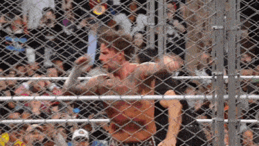 a man behind a chain link fence has a tattoo on his chest