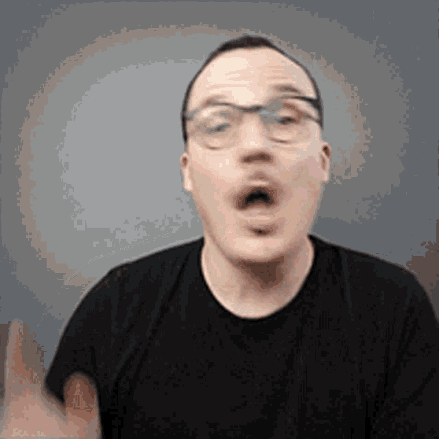 a man wearing glasses and a black shirt is making a funny face