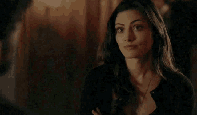 a woman is smiling and looking at the camera while wearing a black shirt .