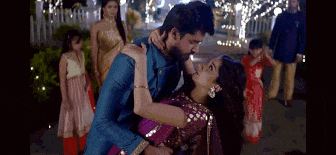 a man is holding a woman in his arms and kissing her .