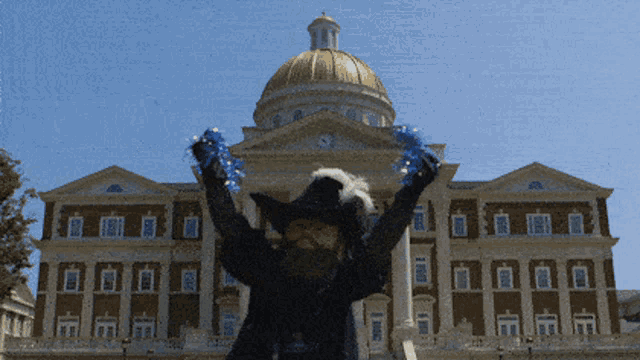 a person in a cowboy hat is standing in front of a building with their arms in the air
