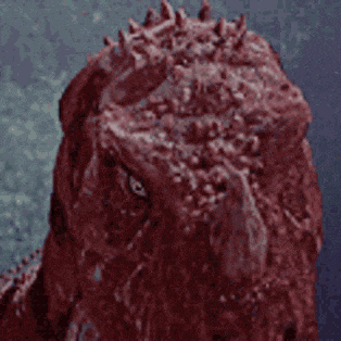 a close up of a red monster 's face with spikes on it .