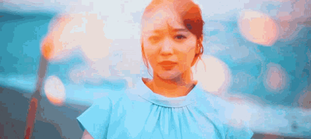 a woman in a blue top looks at the camera