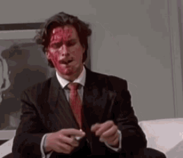 a man in a suit and tie with blood on his face is holding a knife .