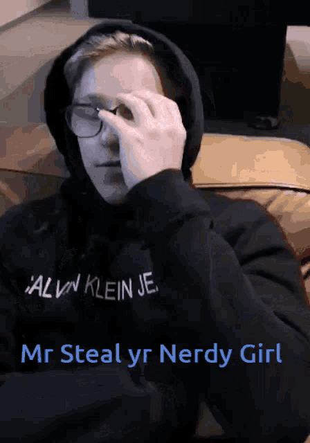 a person wearing a hoodie that says calvin klein je covering their eyes