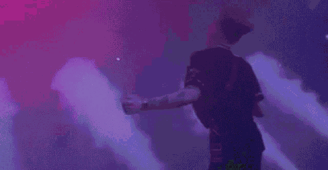 a man is dancing on a stage in front of a purple and pink background .