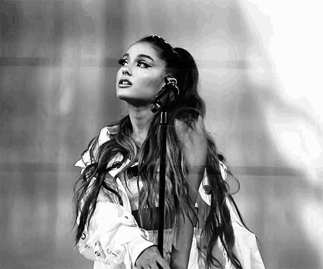 a woman with long hair is singing into a microphone in a black and white photo