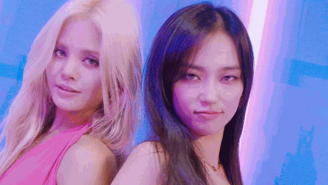 two women are standing next to each other in front of a blue background .