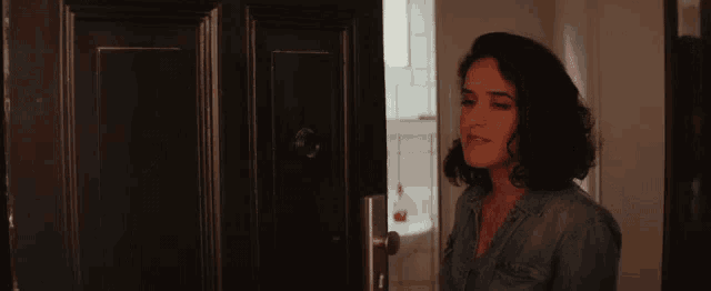 a woman is standing in front of a door and looking out .