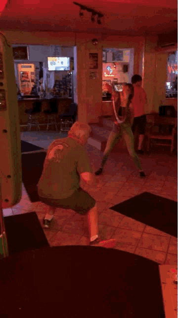 a man and a woman are playing hula hoop in a bar