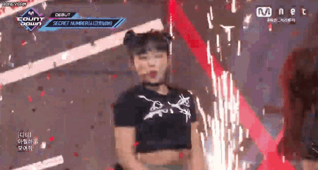 a girl in a black crop top is dancing on a stage with confetti falling around her