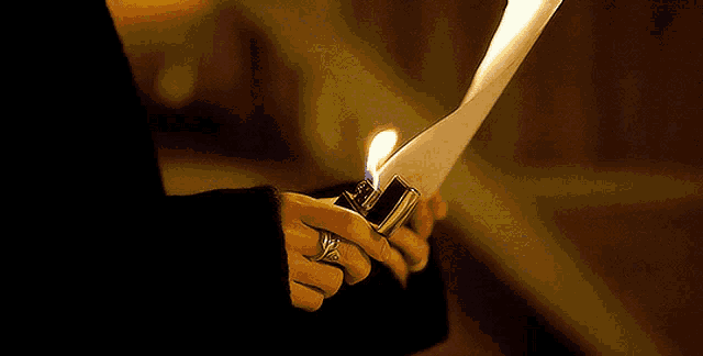a person with a ring on their finger is holding a lit lighter