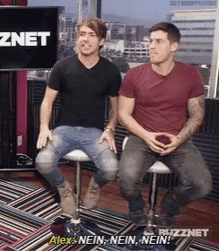 two men are sitting on stools in front of a screen that says alex nein nein nein