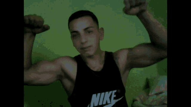 a man wearing a black nike tank top flexes his muscles