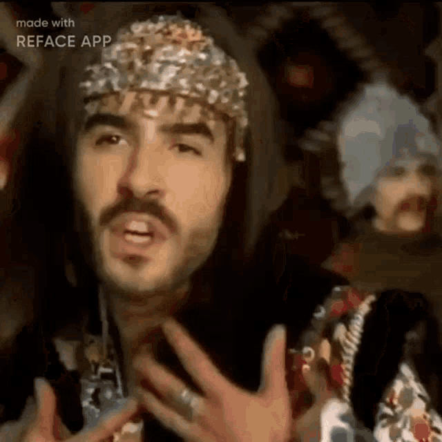 a man with a mustache and a crown on his head is wearing a floral shirt .