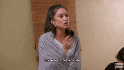 a woman in a striped sweater is standing in a room and yelling at someone .