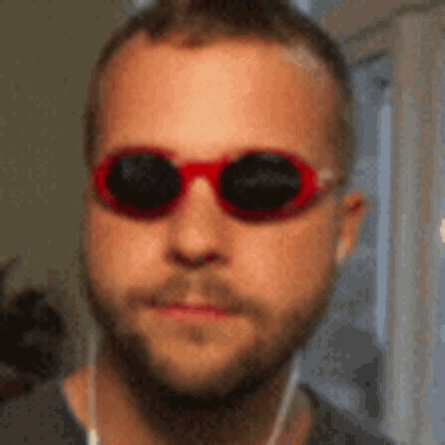 a man wearing a pair of red sunglasses with black lenses