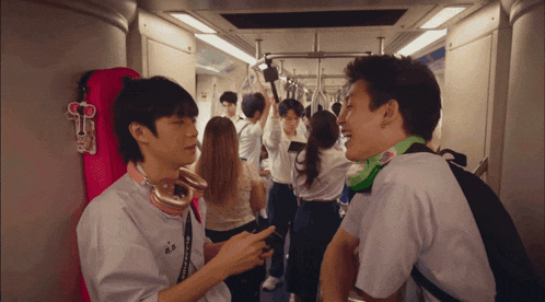 a man wearing a white shirt with the letter a on it is talking to another man