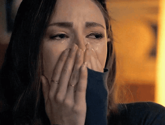 a woman with a ring on her finger is crying and covering her face with her hands