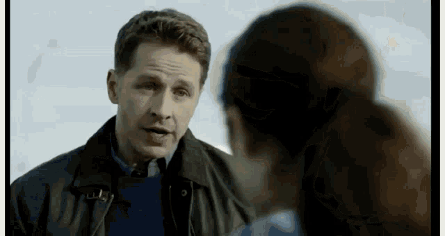 a man in a black jacket is talking to a woman .