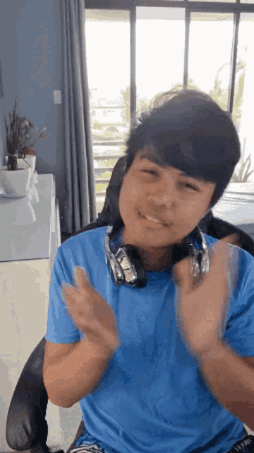 a young man wearing headphones is clapping his hands